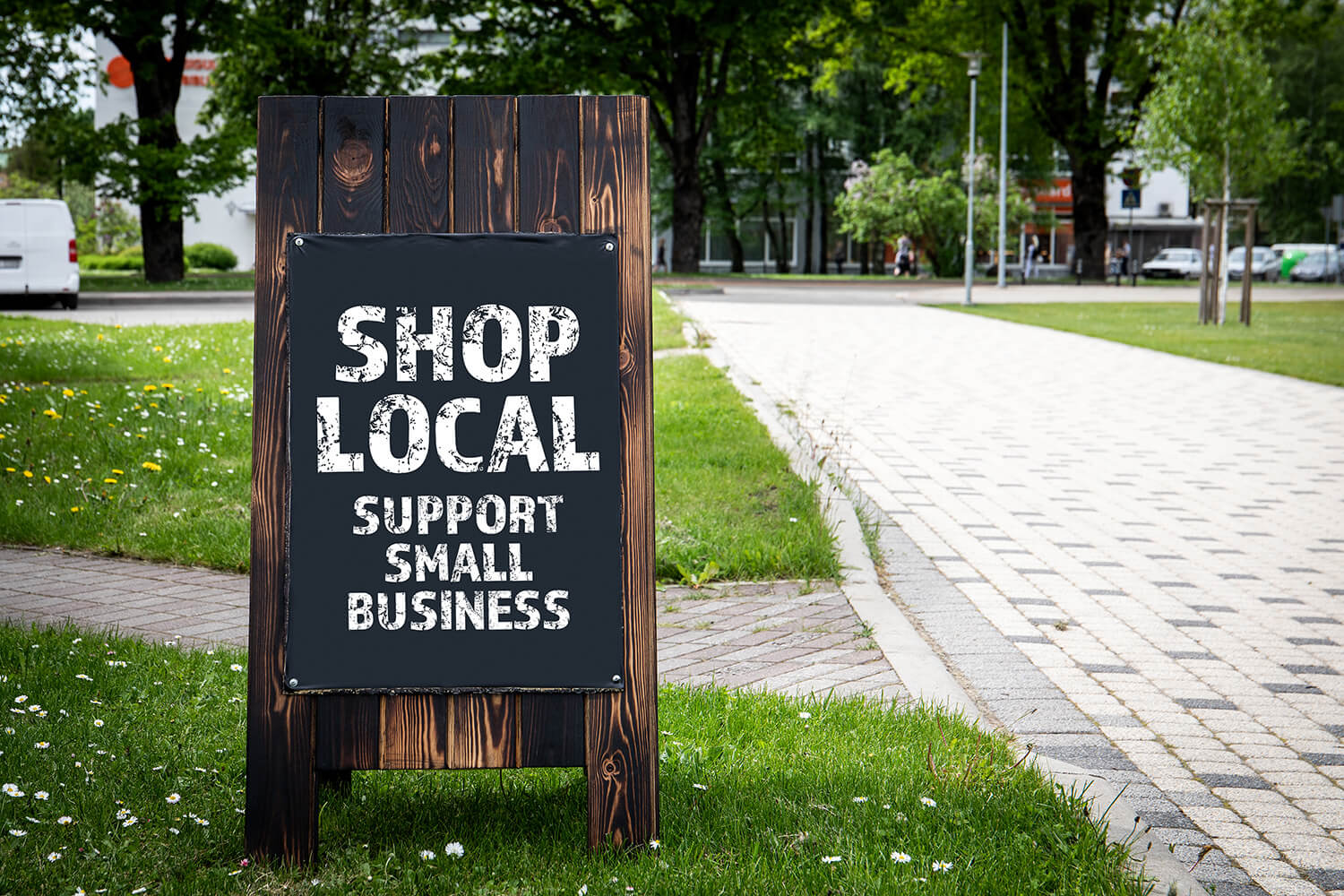 A-Frame sign next to roadway, written on it, "Shop Local, Support Small Business."